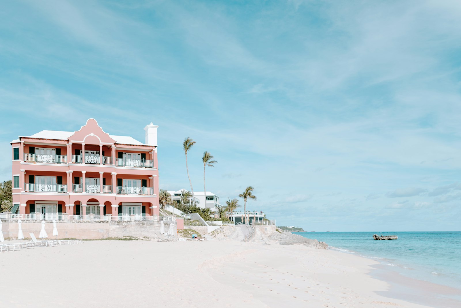 Pink-sand Bermuda beach with a coral-pink beachfront hotel and palm trees