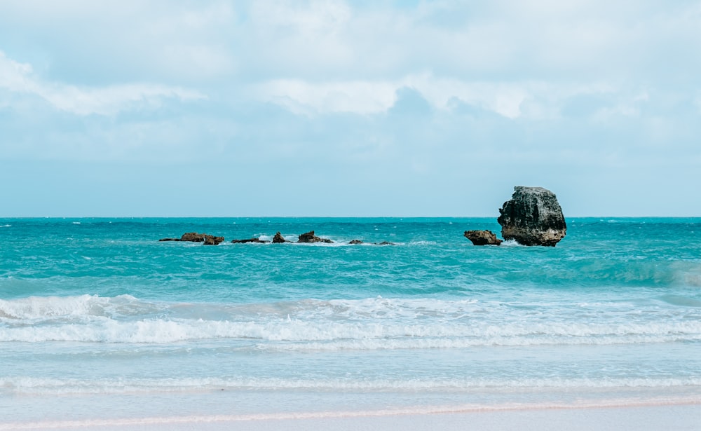 brown rock formation on sea under white clouds during daytime