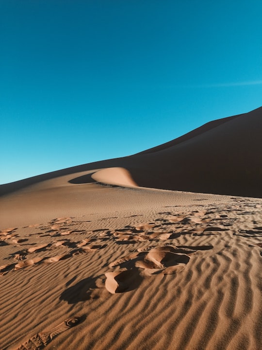brown sand under blue sky during daytime in Erg Chebbi Morocco