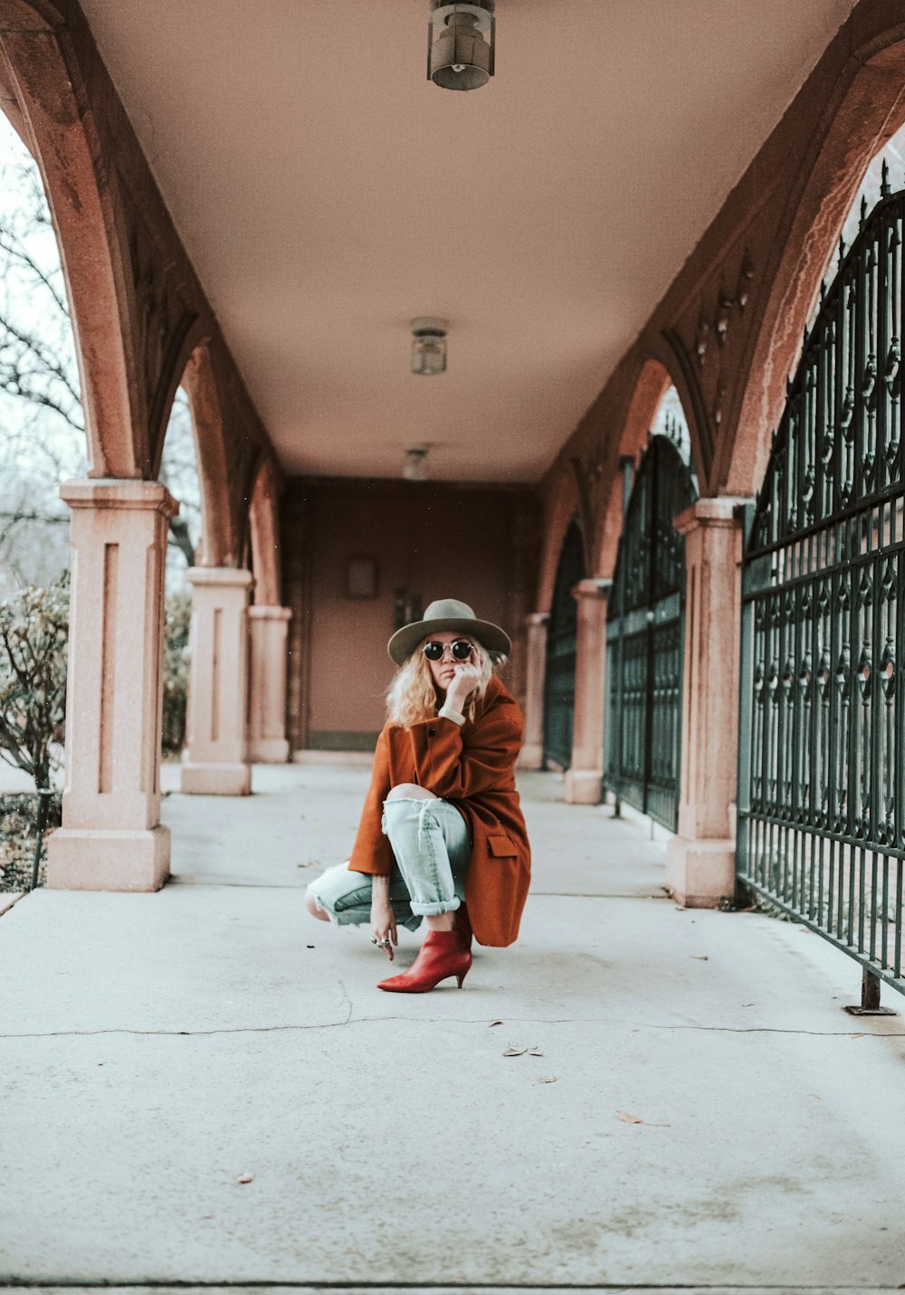 woman in brown coat sitting on concrete floor