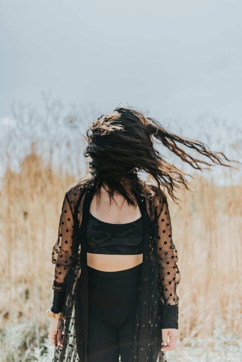 woman in black tank top and brown jacket standing on brown grass field during daytime