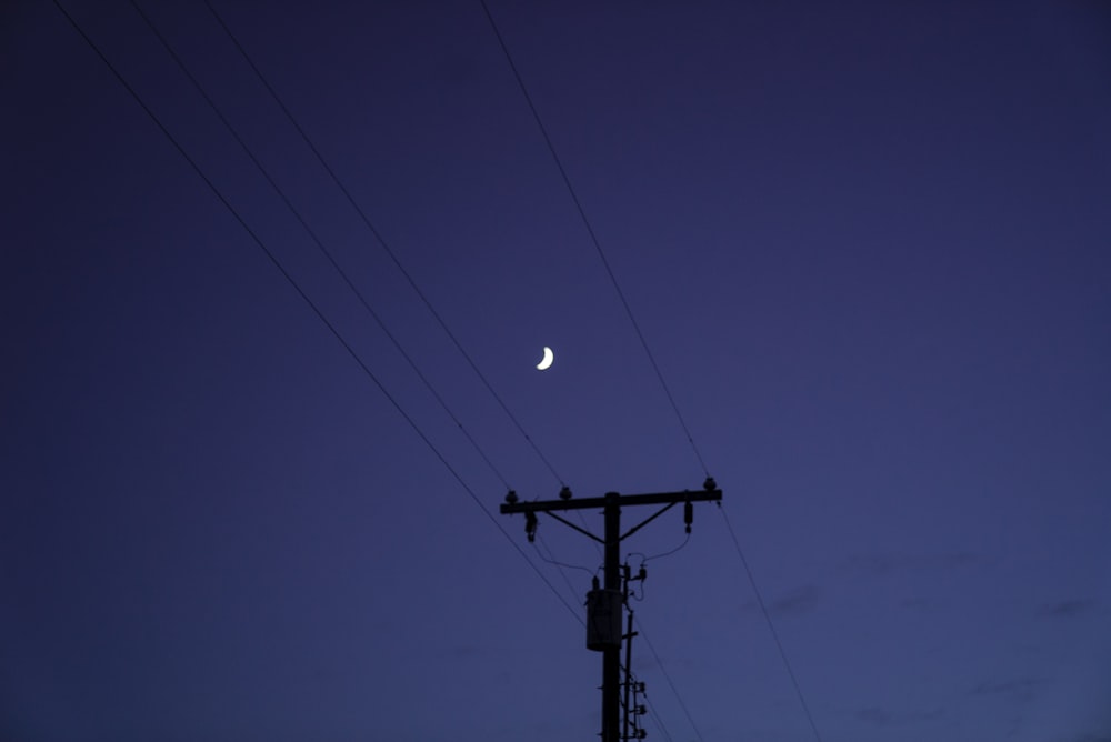 Poste eléctrico negro bajo el cielo azul durante la noche