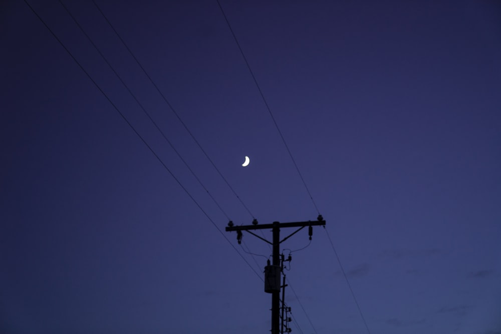 black electric post under blue sky during night time