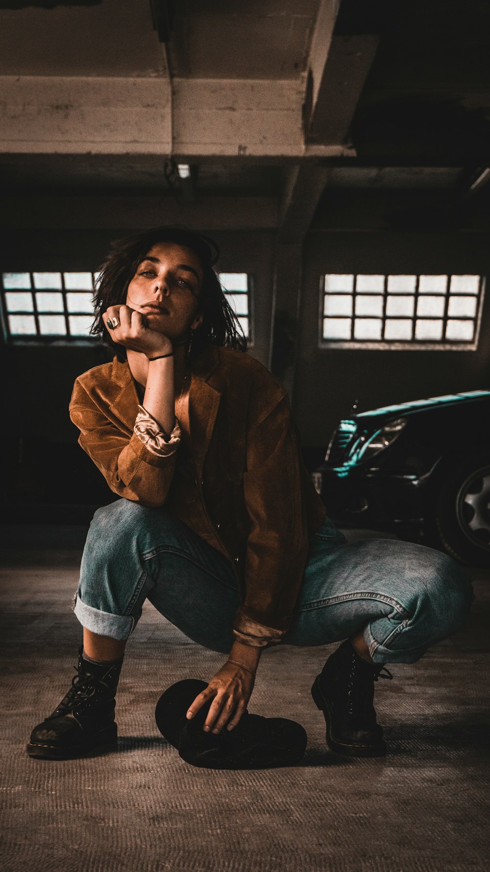 woman in brown jacket and blue denim jeans sitting on floor