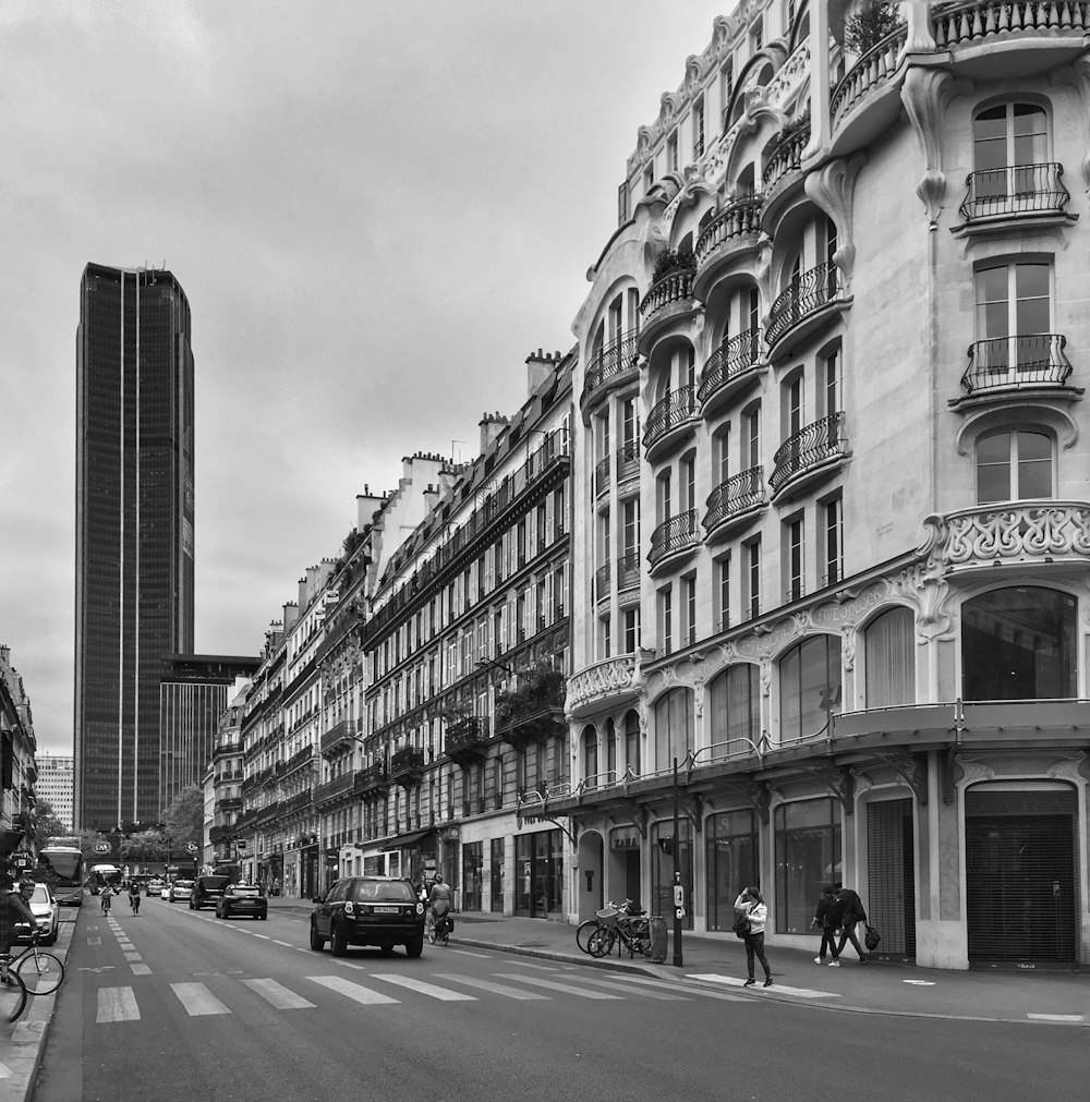 grayscale photo of cars on road near building