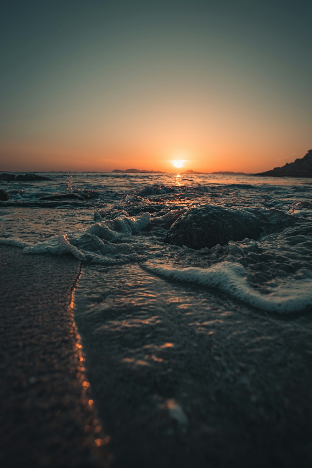 ocean waves crashing on shore during sunset