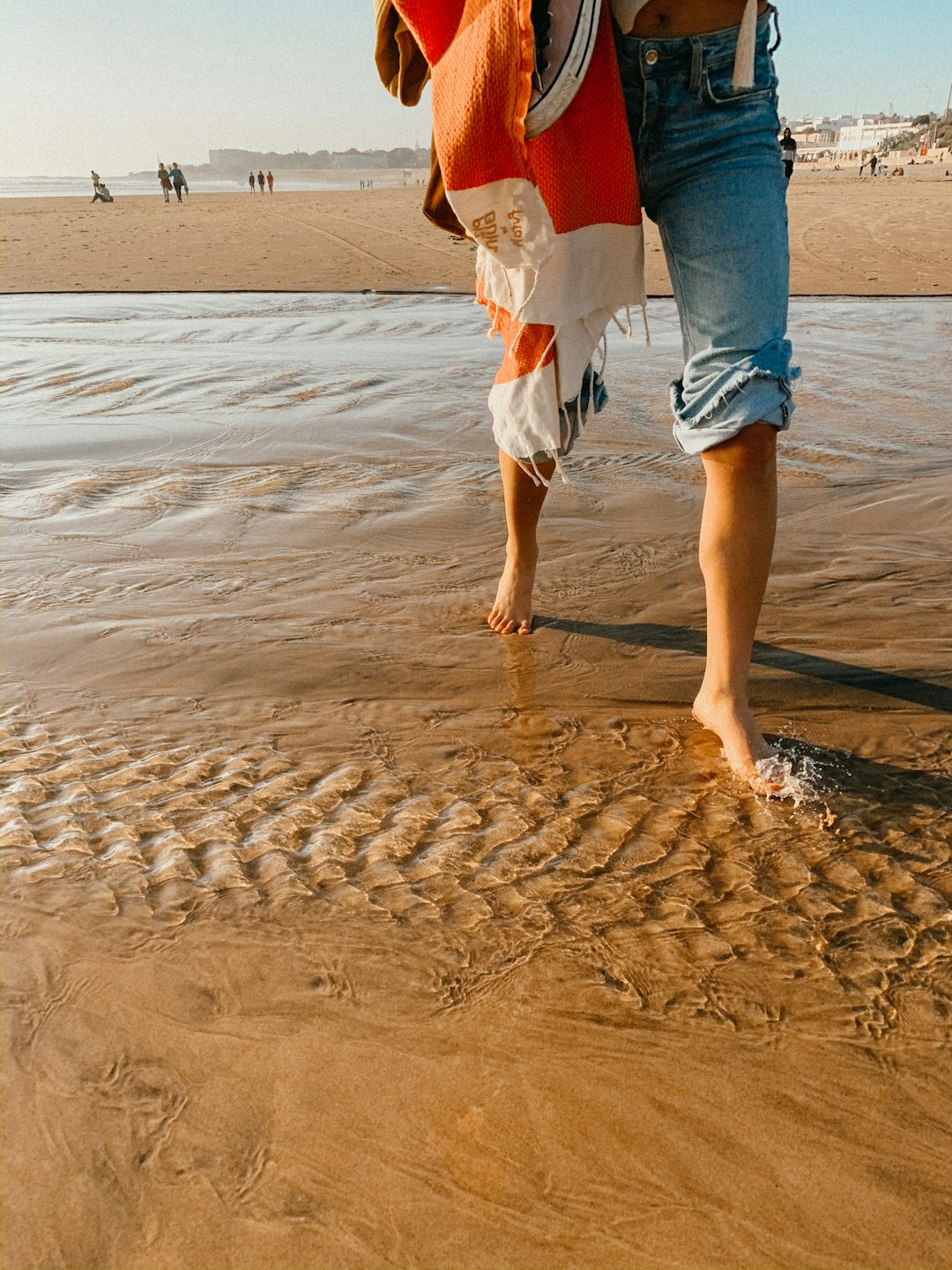 person in blue denim shorts walking on beach during daytime