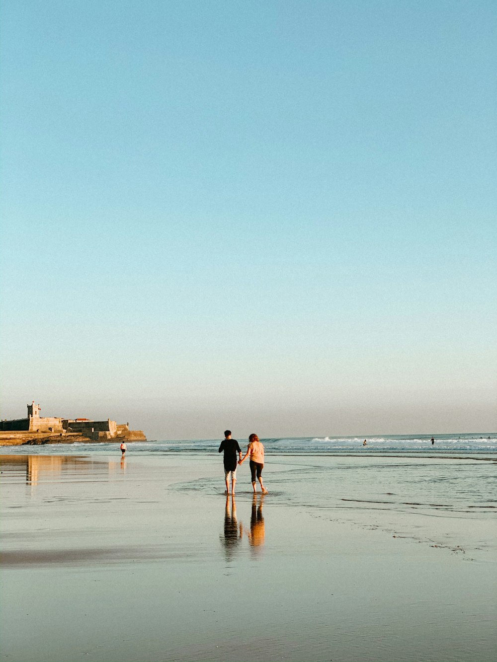 woman in black shirt walking on beach during daytime