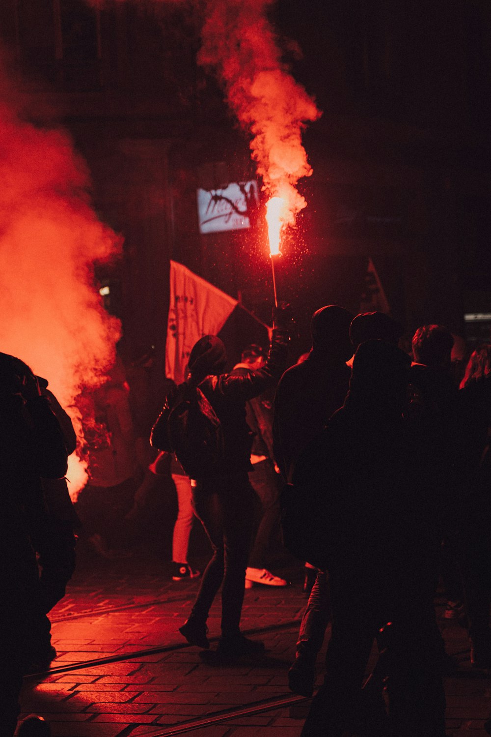 people standing on the street with red smoke
