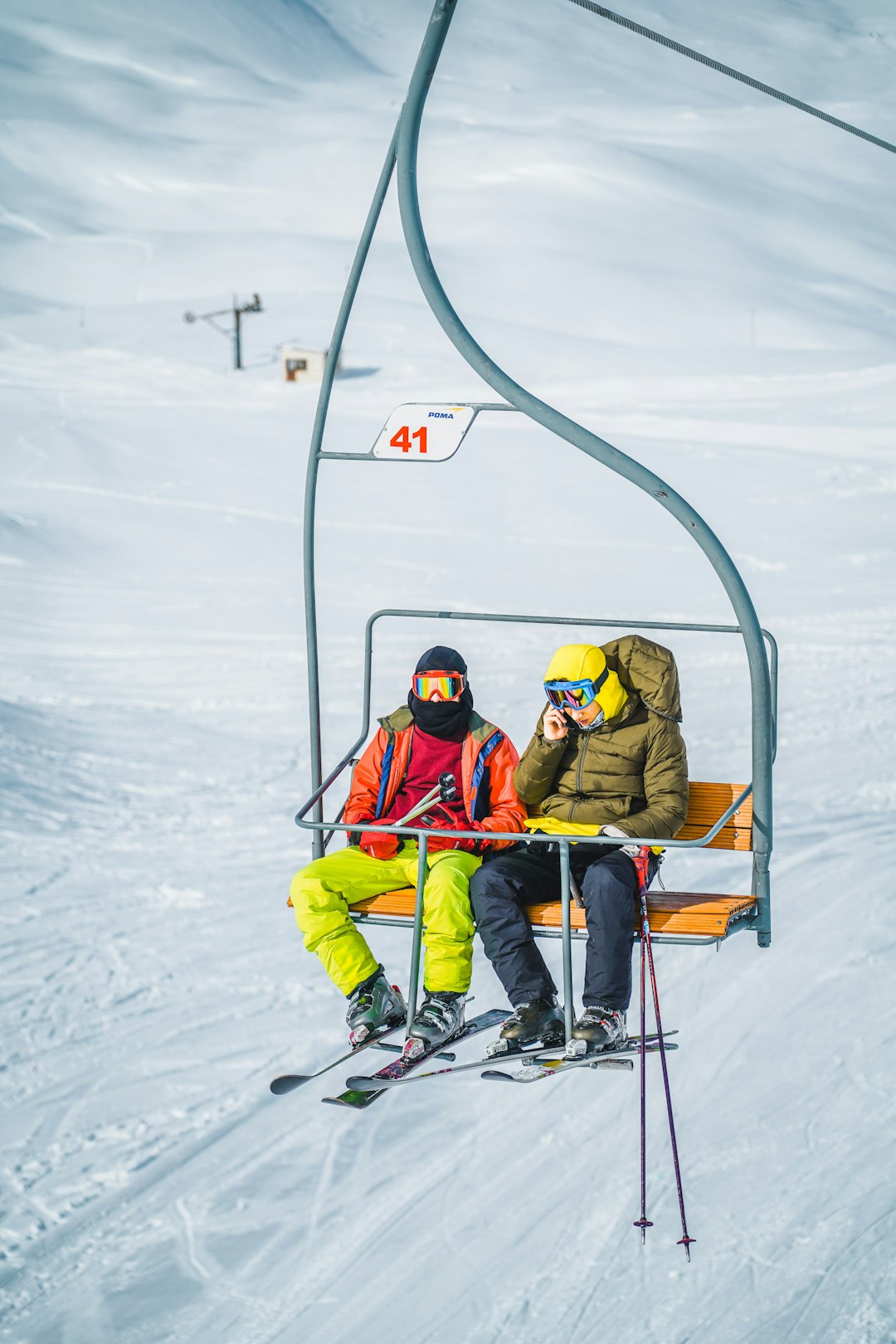 2 children riding ski lift on snow covered ground during daytime
