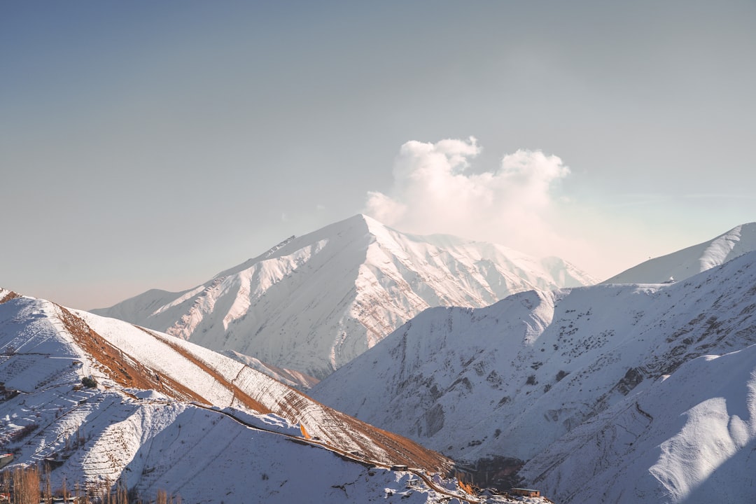 snow covered mountain under white clouds during daytime