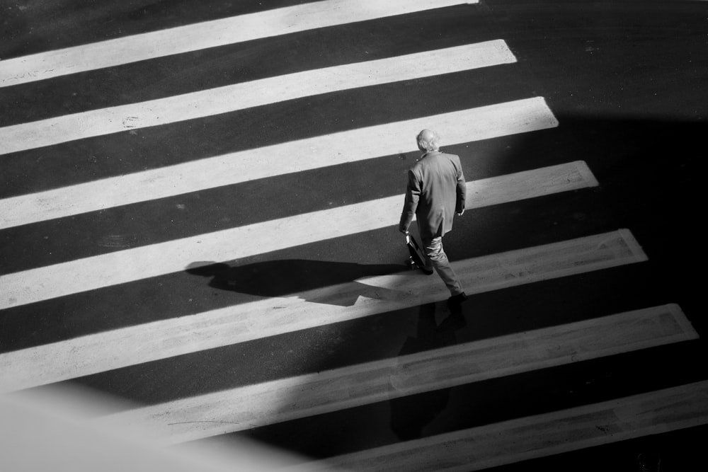 man in white long sleeve shirt walking on pedestrian lane