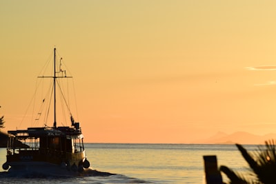 silhouette of boat on sea during sunset