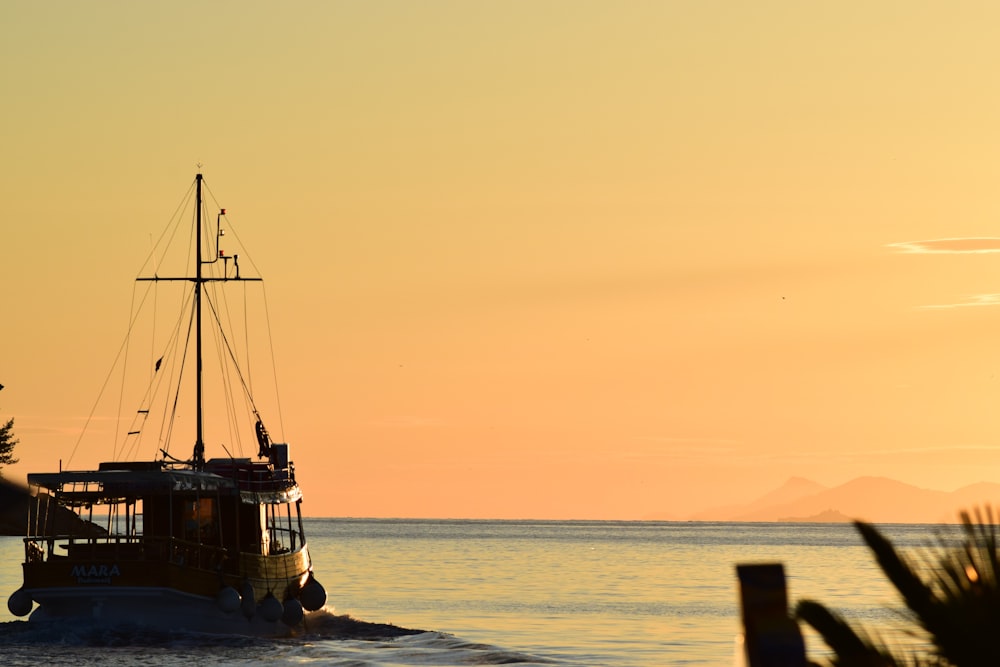 silhouette of boat on sea during sunset