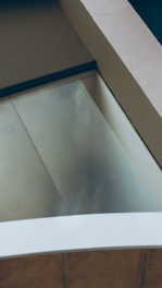 An abstract view of architectural elements featuring intersecting lines and planes with a combination of glass and concrete materials.