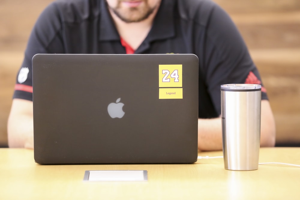 Mann in schwarzer Jacke sitzt vor dem MacBook
