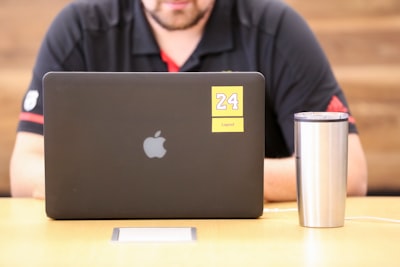 man in black jacket sitting in front of macbook lakers google meet background