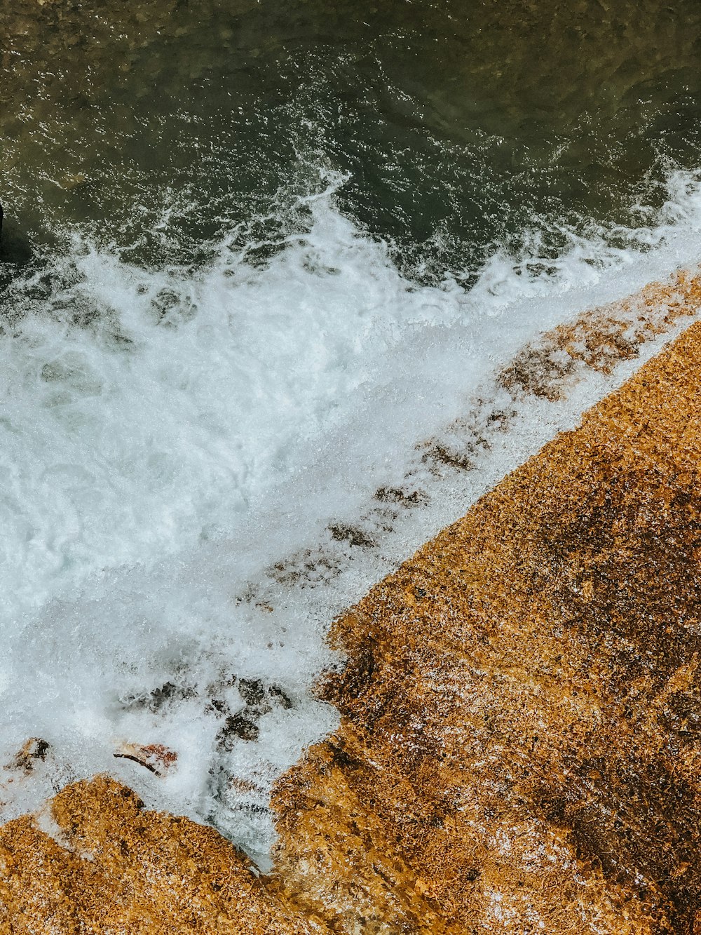 water waves hitting brown sand during daytime