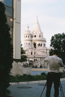 man in white shirt standing in front of white concrete building during daytime