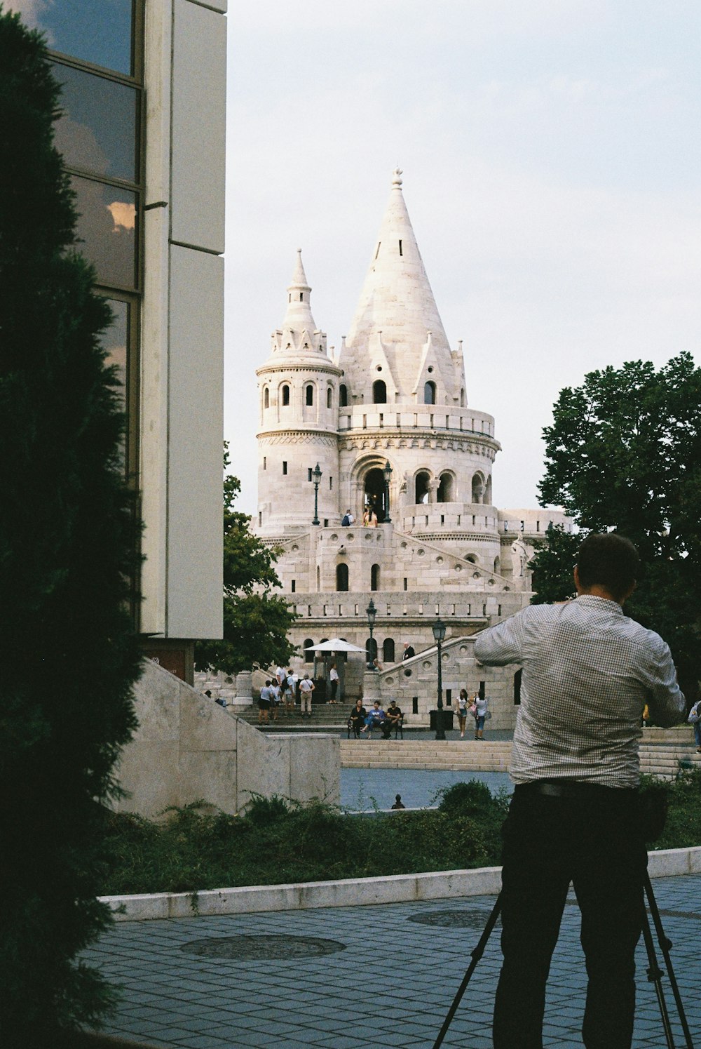 man in white shirt standing in front of white concrete building during daytime