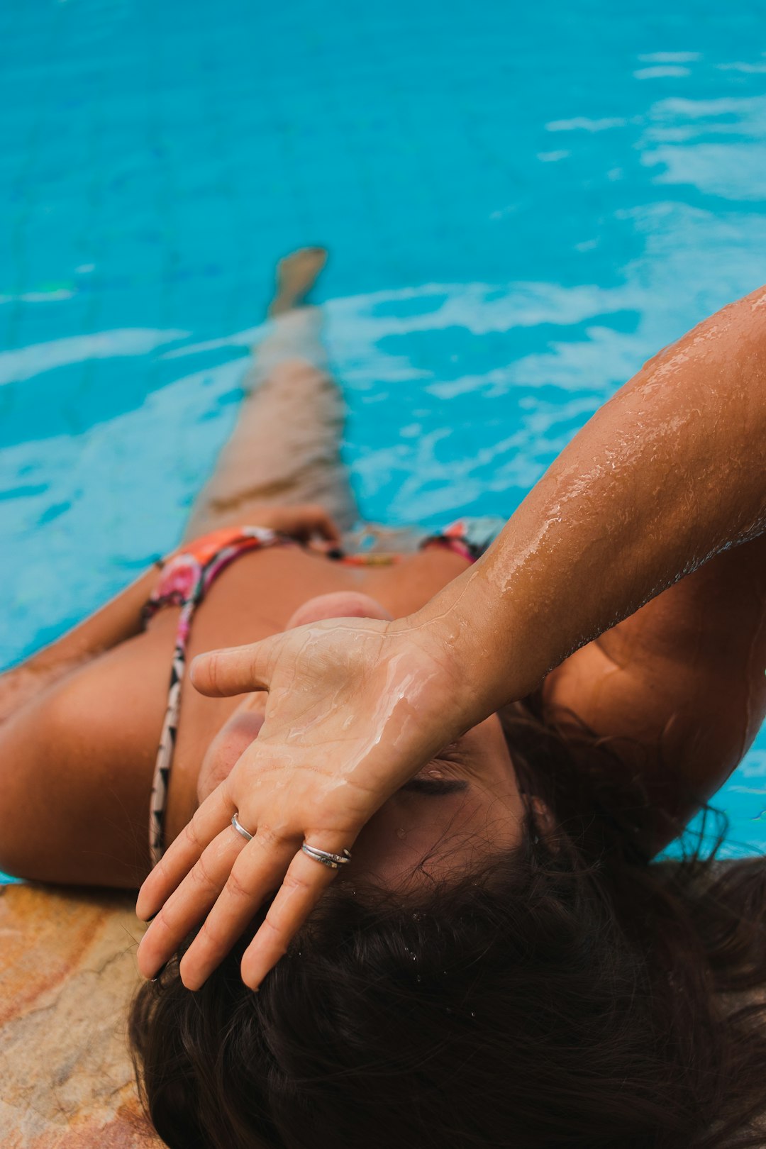 woman in blue and white bikini bottom lying on swimming pool