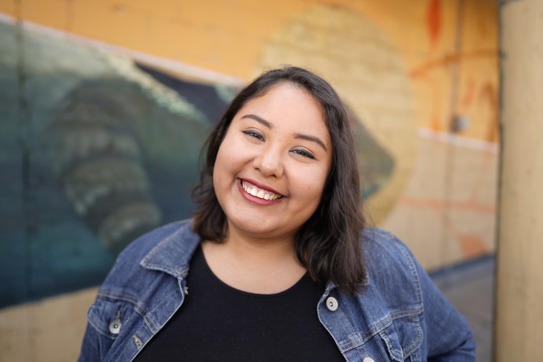 woman in black crew neck shirt and blue denim jacket smiling