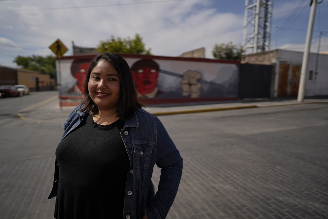 woman in black leather jacket standing on road during daytime