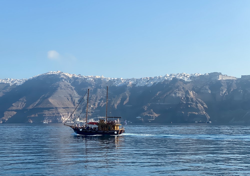 brown boat on sea near snow covered mountain during daytime