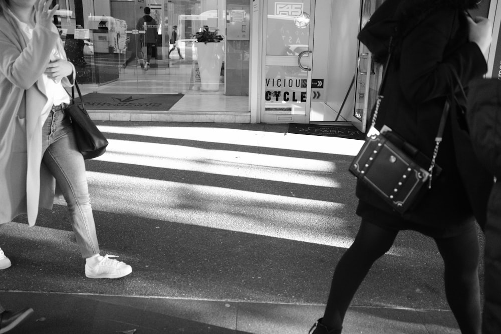 grayscale photo of woman walking on pedestrian lane