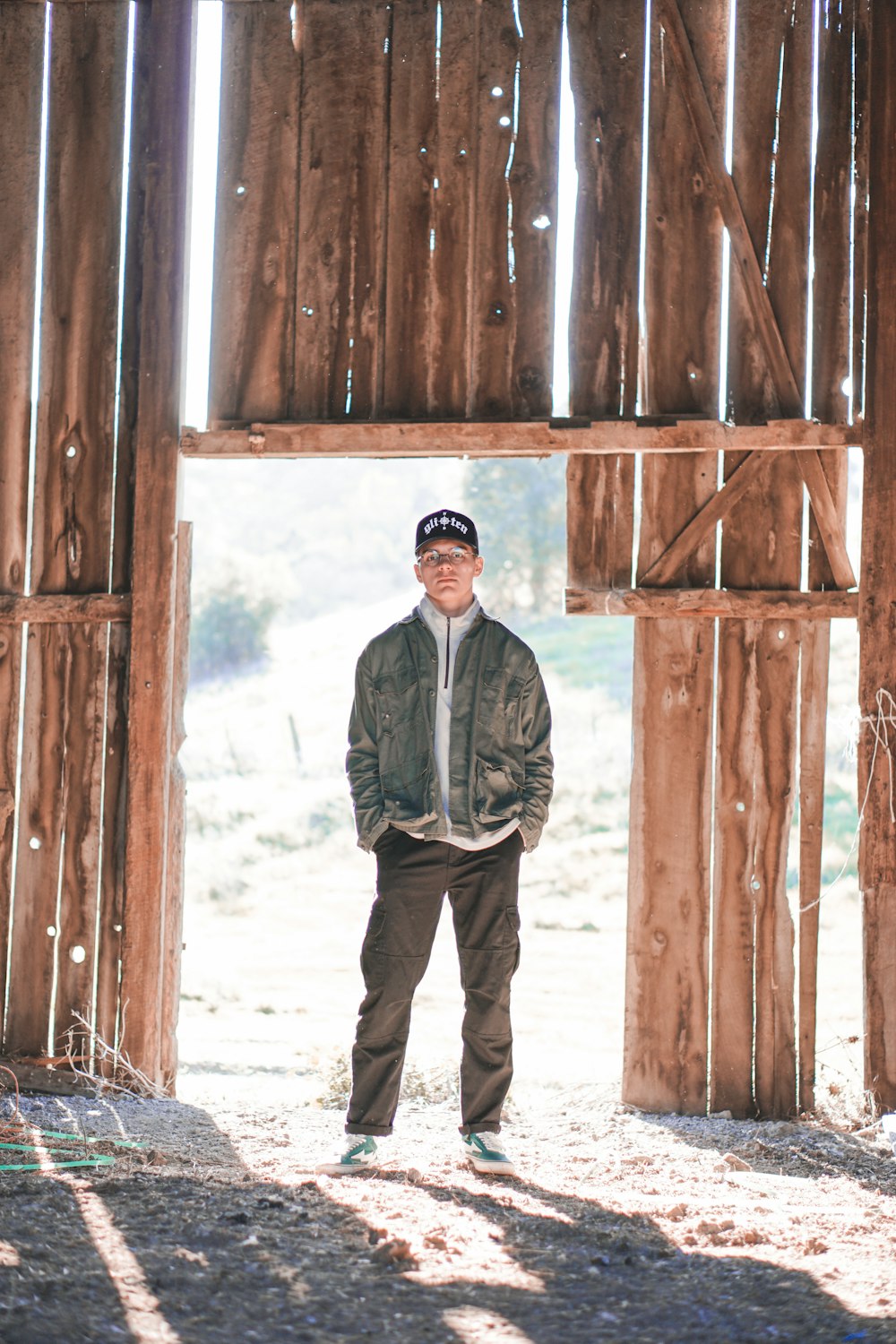 man in gray jacket standing beside brown wooden wall during daytime