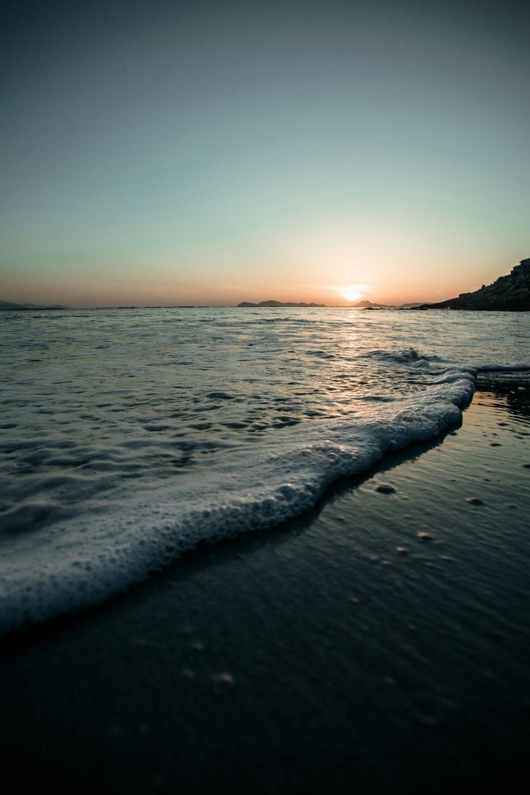 sea waves crashing on shore during sunset