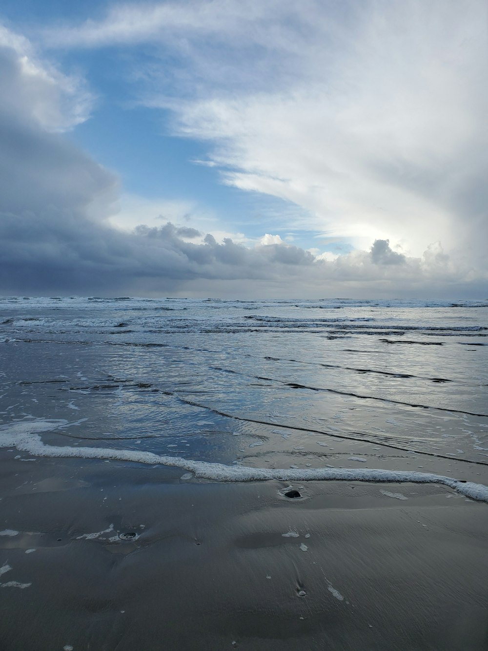 ocean waves crashing on shore under white clouds and blue sky during daytime