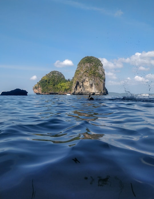 green and brown rock formation on blue sea under blue sky during daytime in หาดถ้ำพระนาง (Phra Nang Cave Beach) Thailand