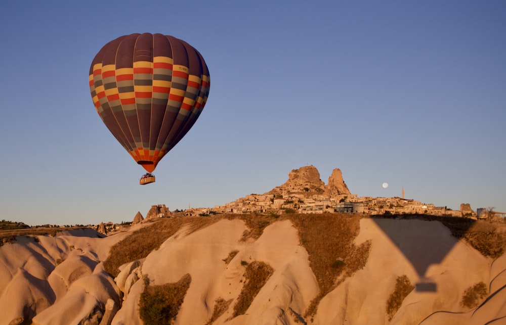 hot air balloon flying over brown mountain during daytime