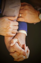 person in blue long sleeve shirt holding babys hand