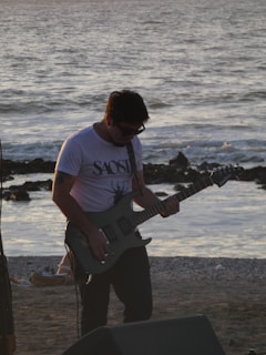 a man playing a guitar on the beach
