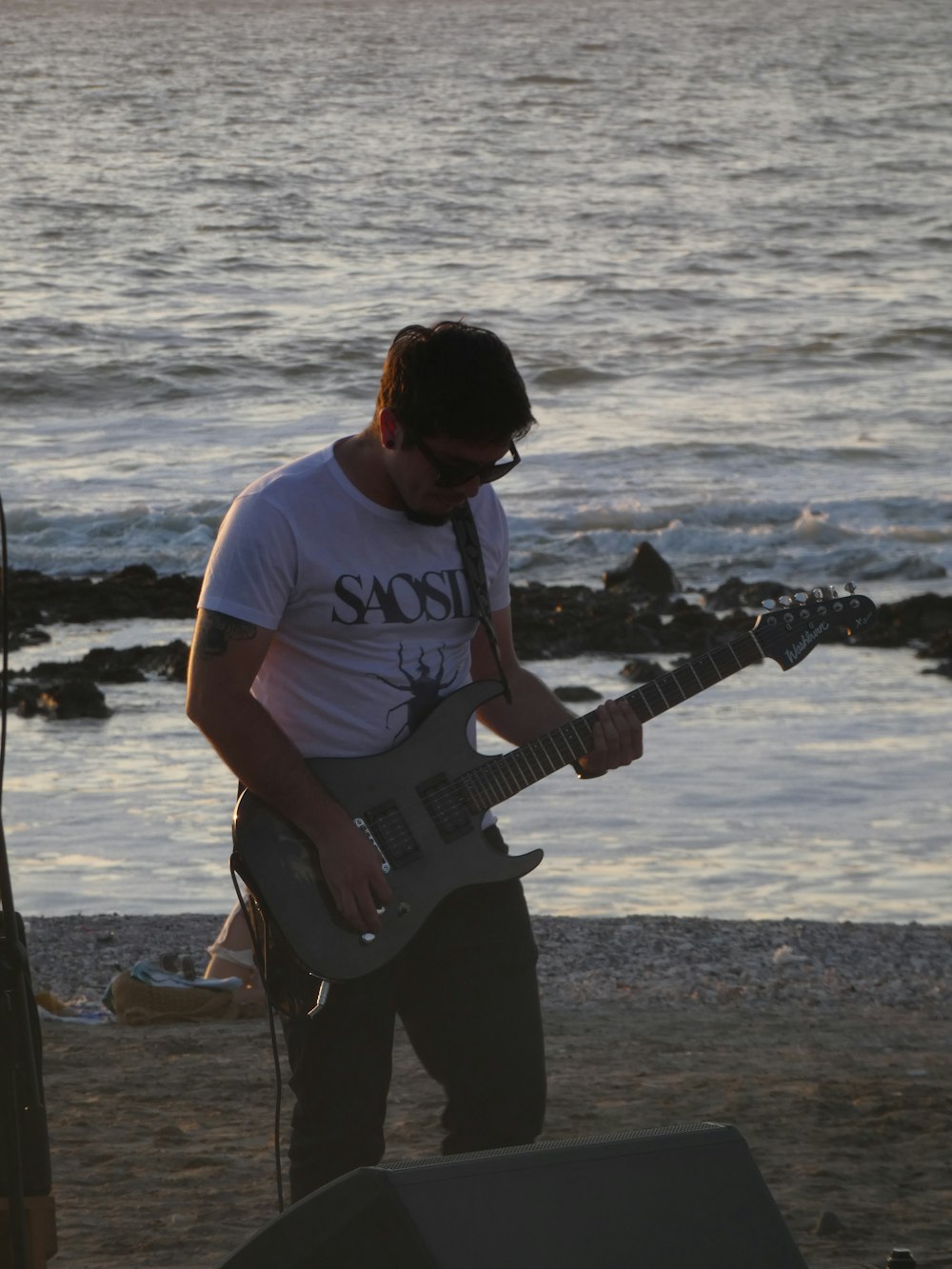 a man playing a guitar on the beach