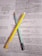 Two pencils, one yellow and one turquoise, are placed on top of pages containing printed text and handwritten notes. The text appears to be from a chemistry book or study material, discussing topics like polymerisation and catalysts. Handwritten annotations and diagrams are visible among the printed words.