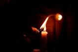 Close-up of a hand lighting a Luma Rituals candle, with warm golden flame.