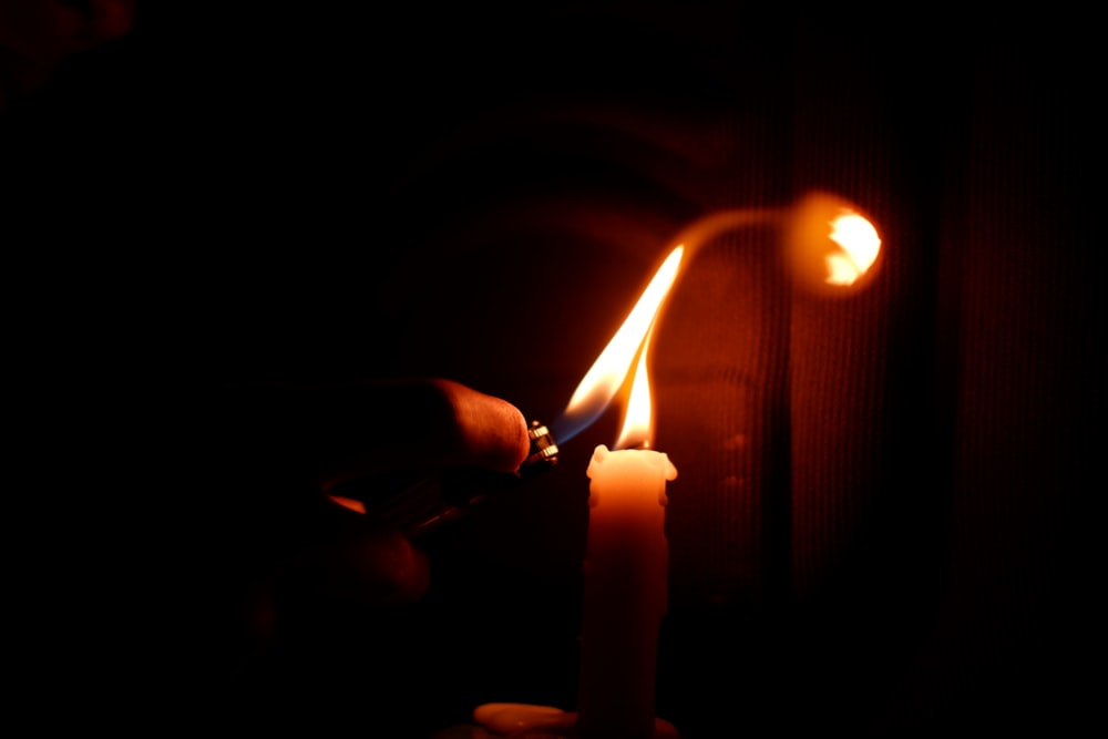 person holding lighted candle in dark room