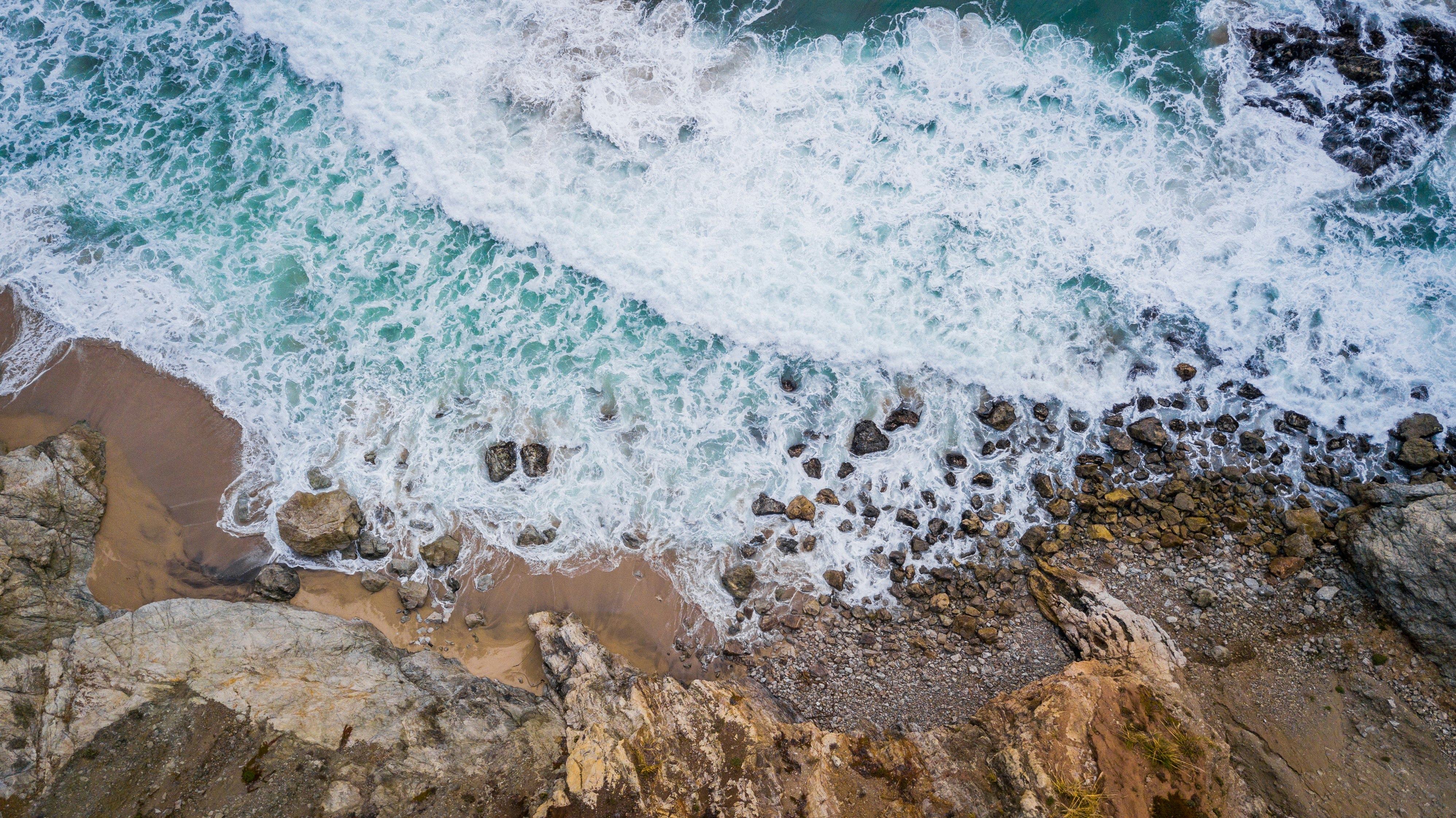 brown rocky shore with ocean waves during daytime