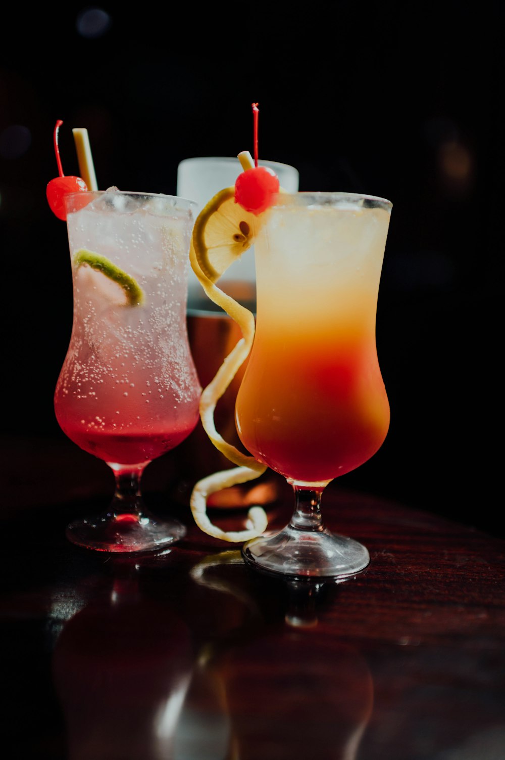 3 clear wine glasses with red liquid and sliced lemon