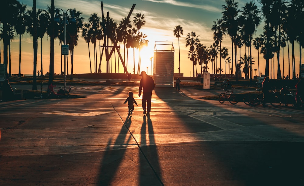 man in black shirt and pants walking on sidewalk during sunset