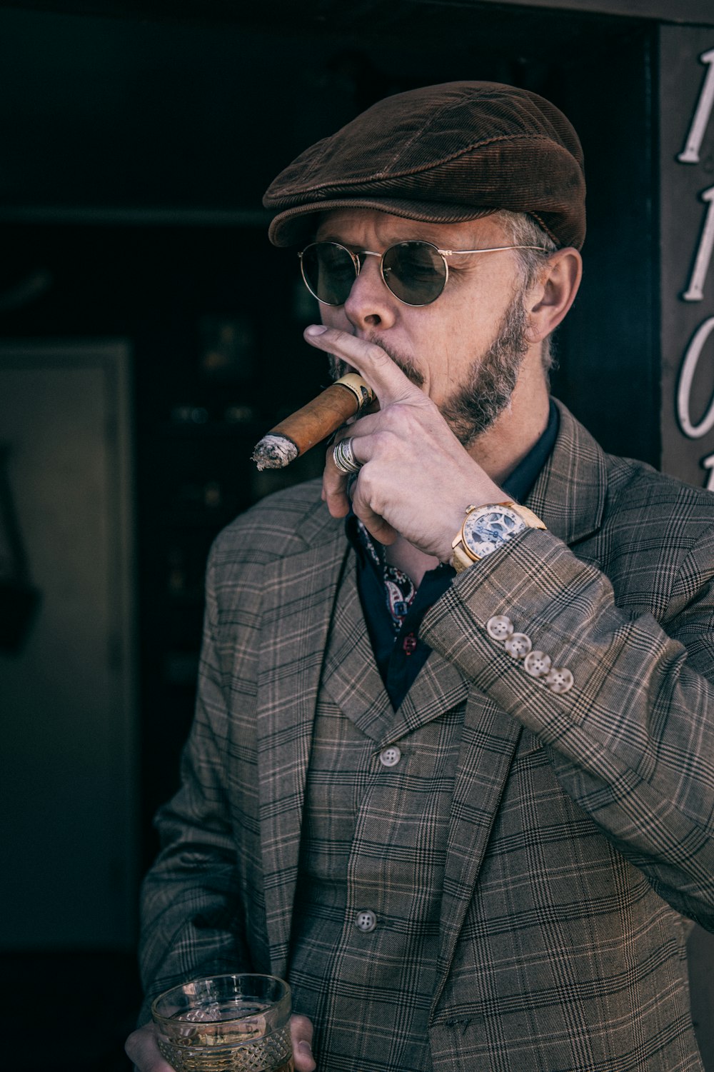 Mann in braun-schwarz kariertem Mantel raucht Zigarette