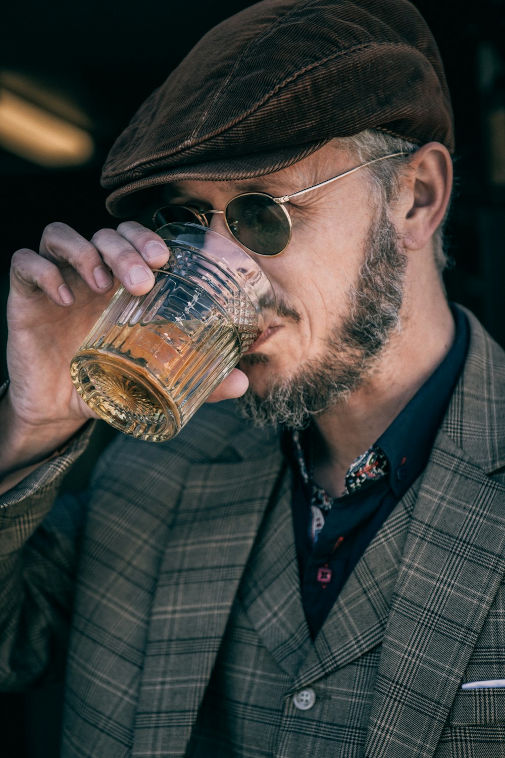 man in black and white plaid suit jacket holding clear drinking glass