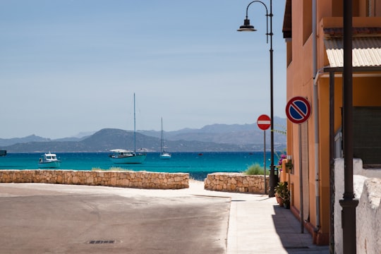 red stop sign on brown wooden post near sea during daytime in Golfo Aranci Italy