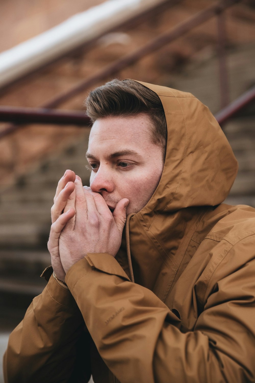 man in brown jacket covering his face