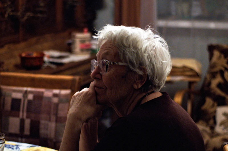An older woman sitting quietly at home, deep in thought