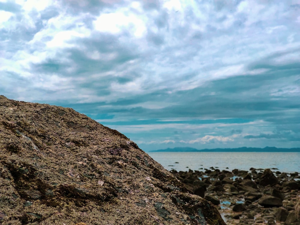 gray rocky shore under white cloudy sky during daytime