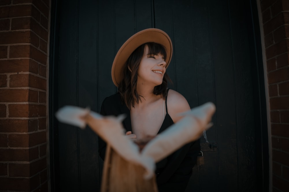 woman in black tank top wearing brown fedora hat